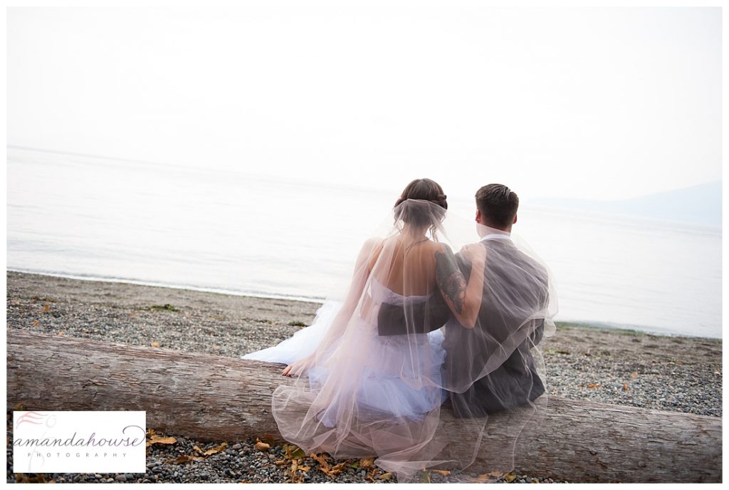 PNW bride and groom sitting on the beach on driftwood in Anacortes | Photographed by Tacoma Wedding Photographer Amanda Howse